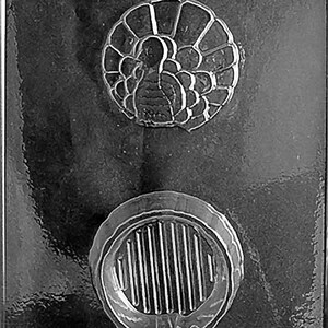 Puede incluir: Un molde de plástico transparente con dos diseños distintos. El diseño superior es un contorno detallado de un pavo, mientras que el diseño inferior es una forma circular con líneas verticales. Este molde es probablemente para crear chocolates o caramelos.