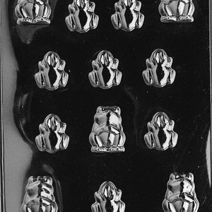 May include: A clear plastic mold with 12 frog-shaped cavities. The mold is designed for making chocolate or candy frogs.