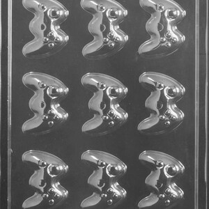 May include: A clear plastic mold for making chocolate game controllers. The mold has nine cavities, each shaped like a video game controller. The mold is labeled "Life of the Party K 169".