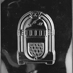 May include: A silver-colored plastic mold for making chocolate candy in the shape of a vintage jukebox. The mold has a detailed design with a record player, speakers, and a coin slot.