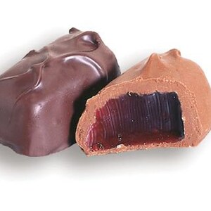 May include: Two chocolate-covered candies, one with a dark chocolate shell and the other with a milk chocolate shell. The milk chocolate candy is cut open to reveal a red jelly filling.