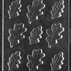 May include: A clear plastic mold with nine individual cavities shaped like oak leaves. The mold is designed for making chocolate or candy.