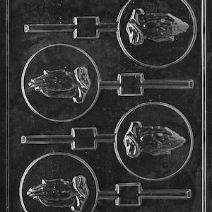 May include: A clear plastic mold for making chocolate lollipops. The mold has four cavities, each shaped like a pair of hands clasped in prayer. The mold is designed to create lollipops with a stick attached.