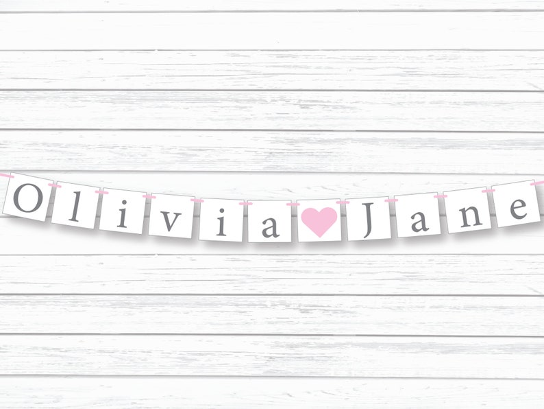 May include: A white banner with pink string and gray letters spelling "Olivia" with a pink heart and "Jane".