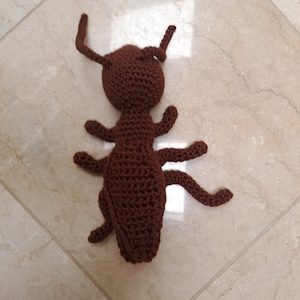May include: A brown crocheted ant toy with long legs and antennae.