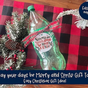 May include: A clear Sprite bottle with a green cap is adorned with a red and green plaid ribbon and a gift tag that reads "May your days be Merry & Sprite!". The bottle is placed on a red and black plaid surface, with festive greenery and a pinecone.