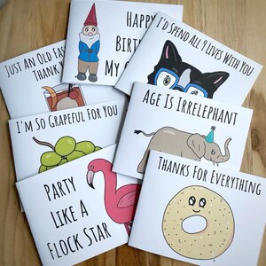 K&ouml;nnte beinhalten: Ein Set mit zehn Gru&szlig;karten mit humorvollen Illustrationen und Text. Die Karten zeigen einen Gnom, eine Katze, einen Elefanten, einen Flamingo, einen Bagel und Trauben. Der Text auf den Karten enth&auml;lt S&auml;tze wie "Happy Birthday", "Ich bin so dankbar f&uuml;r dich" und "Alter ist irrelephant".