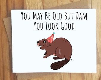 May include: A white card with the text "You may be old but dam you look good" and a cartoon beaver wearing a party hat.