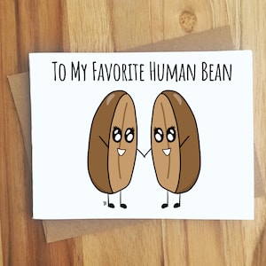 May include: A white card with the text "To my favorite human bean" and a cartoon illustration of two brown beans with faces holding hands.