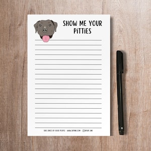 May include: A white lined notepad with a black and gray Pit Bull dog illustration and the text "Show Me Your Pitties". The notepad has the text "Bad Jokes by Good People - www.skpink.com @skp_ink" at the bottom.