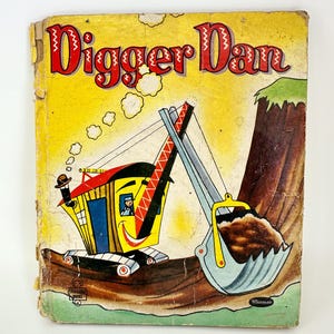 May include: Vintage children's book titled "Digger Dan" with a yellow cover. The cover features a cartoon excavator with a smiling face, digging into a brown mound. The title is in red, stylized lettering.