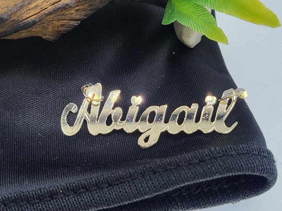 A 14K gold custom name pendant in flowing script — strong demand signal (53 favorites) and a classic personalized fine jewelry piece that reads as genuinely giftable.