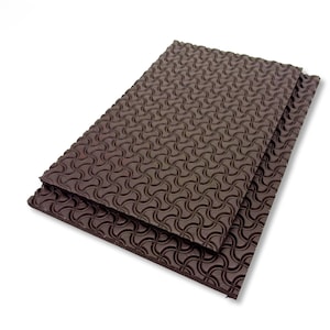 May include: Two rectangular, dark brown foam sheets with a repeating, wave-like pattern. The sheets are stacked, with one slightly overlapping the other. The textured surface is visible, and the background is white.