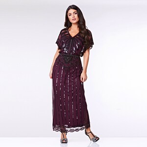 May include: A long, sequined dress in a deep burgundy colour with a black beaded belt. The dress has a V-neckline and short sleeves.
