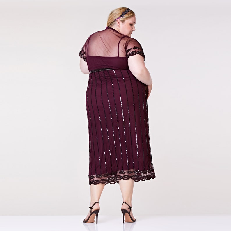 May include: A burgundy midi dress with a sheer overlay and black sequins. The dress has a scalloped hem and a fitted silhouette.