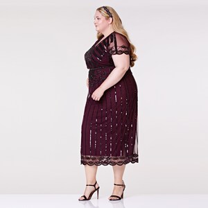 May include: A burgundy midi dress with black sequins and beading. The dress has a V-neckline, short sleeves, and a fitted bodice. It features a black belt and a scalloped hem.
