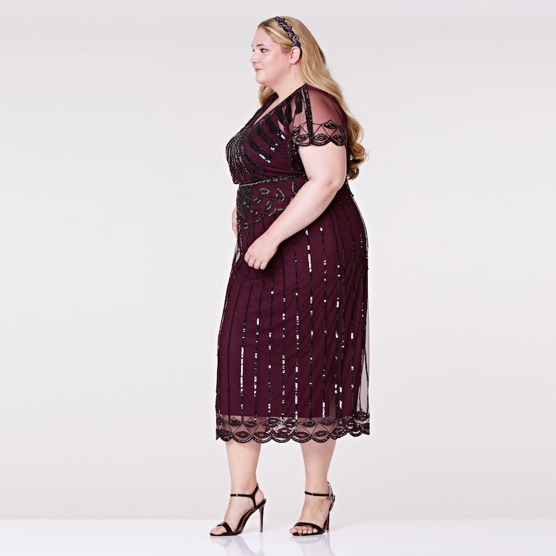 May include: A burgundy midi dress with black sequins and beading. The dress has a V-neckline, short sleeves, and a fitted bodice. It features a black belt and a scalloped hem.