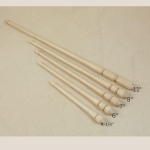 May include: Five light-colored wooden wands arranged diagonally by size, labeled with lengths of 4-1/4 inches, 6 inches, 7 inches, 8 inches, and 11 inches. Each wand features a tapered shaft and a rounded, decorative handle section at the base.