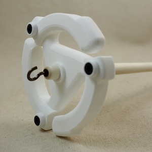 May include: White spinning wheel with a wooden spindle and a metal hook. The wheel has four black accents.