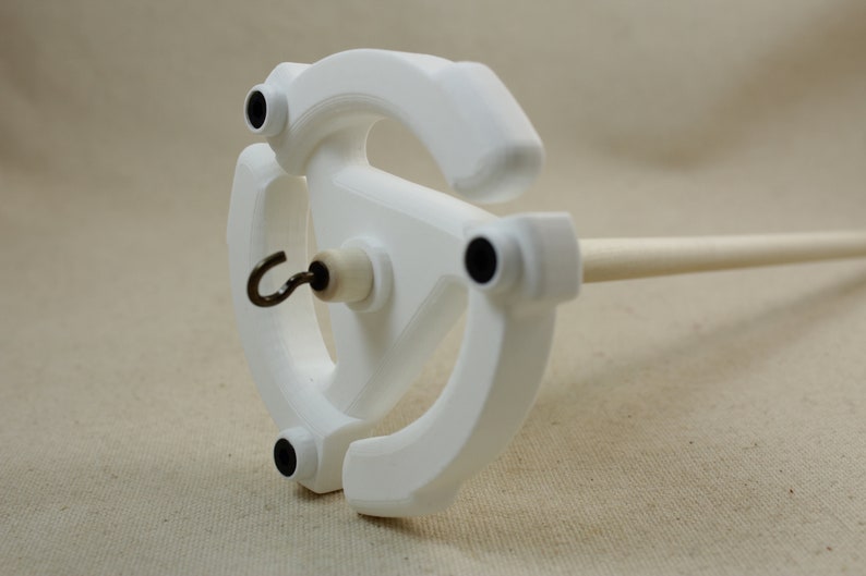 May include: White spinning wheel with a wooden spindle and a metal hook. The wheel has four black accents.