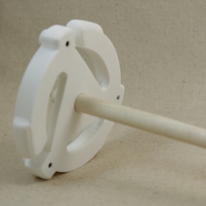 May include: White ceramic spinning wheel with a wooden spindle. The wheel has a unique design with three holes.