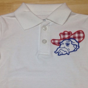 May include: White polo shirt with a blue and red embroidered logo of a cartoon character wearing a red and white checkered hat.