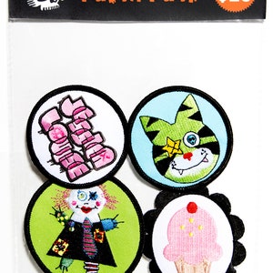 Puede incluir: Un conjunto de cuatro parches bordados para planchar. Los parches son redondos y presentan una magdalena rosa, un gato verde con un parche de ojo de calavera, una mu&ntilde;eca verde y rosa y un parche de texto rosa y blanco que dice "Teenage Wasteland".