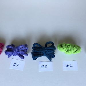 May include: Five spools of cotton cord in different colors, from left to right: pink, purple, teal, green, and light blue. The spools are labeled #5, #4, #3, #2, and #1.