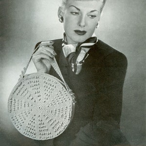 May include: A woman wearing a white crocheted hat and a black jacket holds a round crocheted bag with a strap.