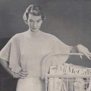 May include: A woman wearing a white knitted sweater with a high neckline and short sleeves. She is standing next to a wicker basket filled with magazines. The magazines have the text "McCall's" on the cover.