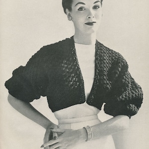 May include: A black cropped cardigan with a V-neckline and puffed sleeves. The cardigan is made of a textured knit fabric.