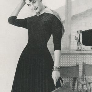 May include: A vintage black dress with a fitted bodice and a flared skirt. The dress has a ribbed texture and three-quarter sleeves. The woman is wearing a bracelet and holding a briefcase. The image is in black and white.
