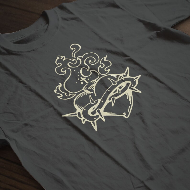 May include: A dark gray t-shirt with a white graphic of a heart with thorns and flames.