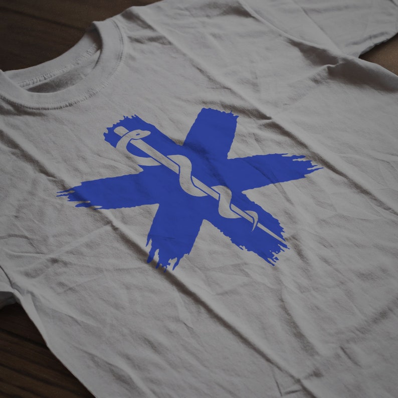 Op de afbeelding: Een wit T-shirt met een blauw medisch symbool. Het symbool is een ster met een slang eromheen gewikkeld.