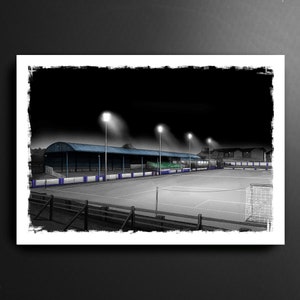 May include: A black and white illustration of a soccer field at night with floodlights illuminating the field. The field is surrounded by a fence and bleachers. There is a goal at the far end of the field.