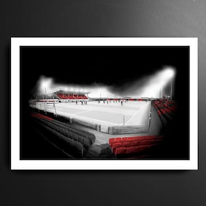 May include: A black and white illustration of a soccer stadium with red seats. The stadium is empty except for a few players on the field.
