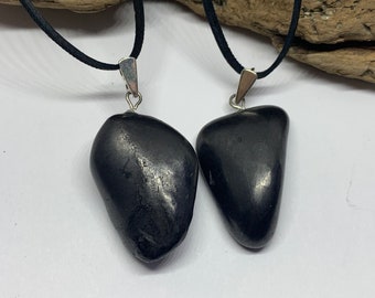 May include: Two black stone pendants on black cords. The stones are smooth and have a slightly shiny finish.