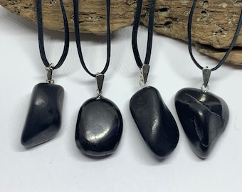 May include: Four black gemstone pendants on black suede cords. The pendants are smooth and polished, with a variety of shapes.
