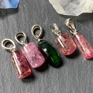 May include: Five gemstone pendants on silver chains. Four pendants are pink tourmaline, one is green tourmaline.