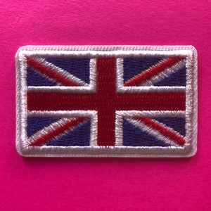 May include: Embroidered rectangular patch featuring the Union Jack, the national flag of the United Kingdom. The design includes a blue background with red and white diagonal stripes and a red cross. The patch has a white border.
