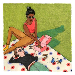 May include: Two people are sitting on a blanket with a pink box and various shoes. One person is wearing sunglasses and a red tank top. The other person is wearing a black shirt and sunglasses. The blanket has a floral pattern.