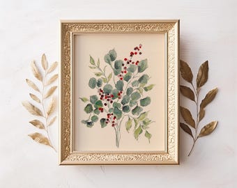 Puede incluir: Una pintura de acuarela enmarcada de un arreglo botánico con hojas verdes de eucalipto y bayas rojas. La obra de arte está enmarcada en un marco dorado ornamentado, con detalles de hojas doradas sobre un fondo blanco.