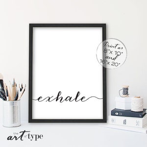 May include: A black framed art print featuring the word "exhale" in cursive. The print is on a white background and available in 20.3cm x 25.4cm and 40.6cm x 50.8cm sizes. The art is from "the art of type".