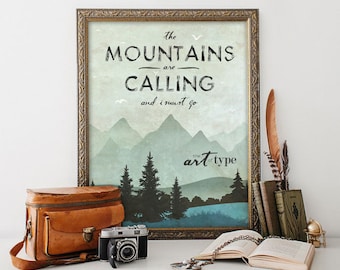 May include: A framed print with a vintage aesthetic featuring a mountain landscape and the text "The Mountains are Calling and I Must Go." The print is in a gold frame and has a blue and green colour scheme. The text "The Art of Type" is also included in the bottom right corner.