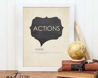 Op de afbeelding: Zwart-wit typografieprint met de woorden "ACTIONS" in een spreekballon en "words" eronder. De print is ingelijst in een wit frame en heeft een vintage esthetiek.