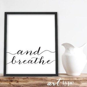 May include: Black and white framed print with the text "and breathe" in a cursive font.