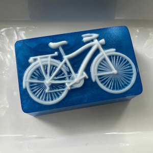 Pode incluir: Uma barra de sabão azul com um desenho de bicicleta branca.