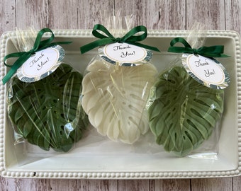 May include: Three green and white leaf-shaped soaps with a thank you tag attached to each. The soaps are packaged in clear plastic bags with green ribbons.