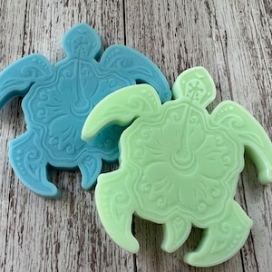May include: Two decorative turtle-shaped soaps, one blue and one green, with intricate floral designs. The soaps are made in the shape of a turtle with a flower in the center.