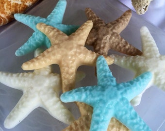 May include: A collection of five starfish soap bars in various colors, including light blue, beige, and white. The soaps are arranged on a white surface.